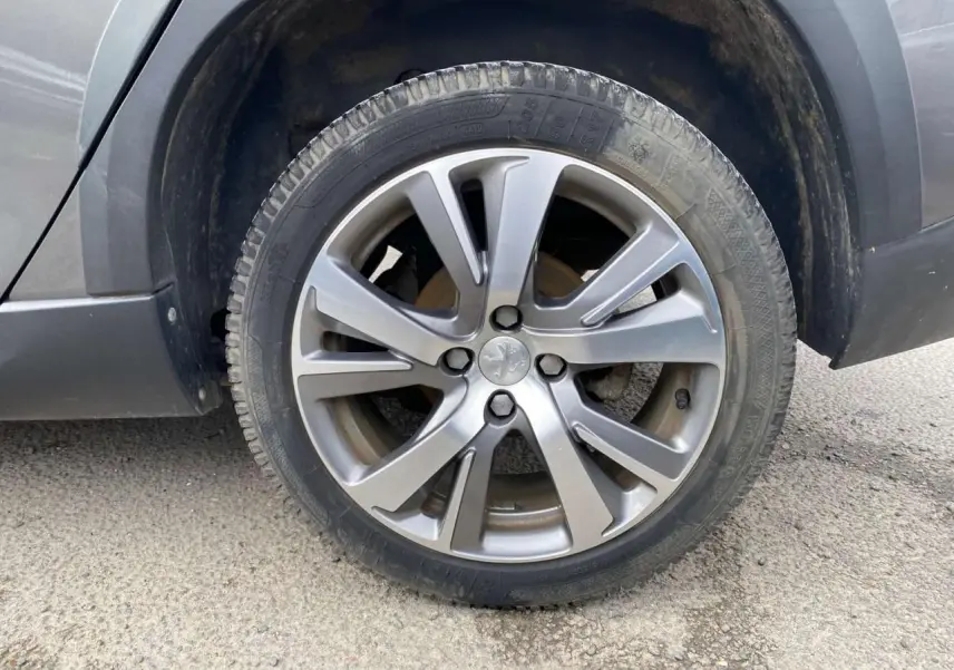 Gros plan sur la roue avant droite d’un Peugeot 2008 gris platinium, mettant en valeur la jante alliage à cinq doubles branches.