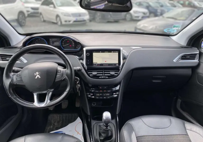 Vue intérieure avant du Peugeot 2008 gris platinium de 2019, avec tableau de bord moderne et boîte manuelle visible.