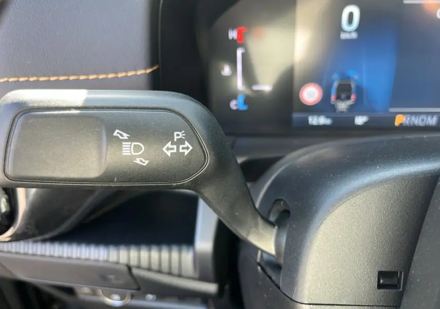 Gros plan sur la commande de clignotants et feux du Ford Ranger PHEV 281 Wildtrak, intérieur noir avec surpiqûres marron.