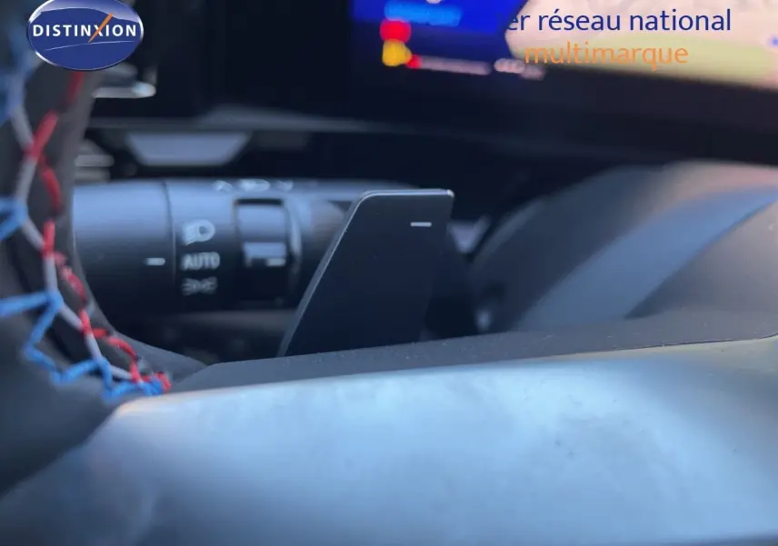 Gros plan sur le volant noir avec surpiqûres rouges et palettes de changement de vitesse du Renault Austral E-Tech hybride.