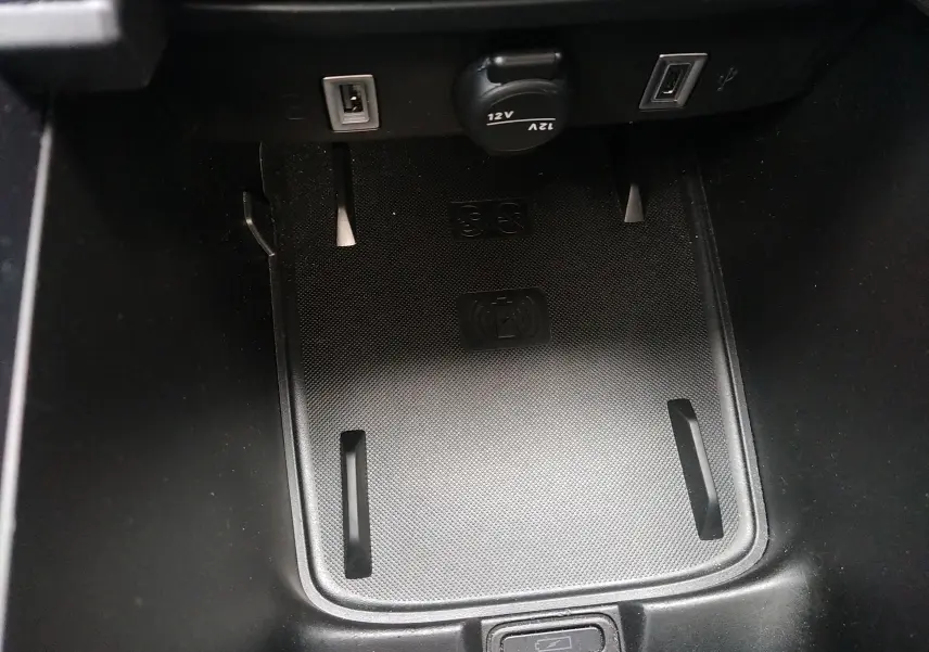Vue rapprochée de la zone de recharge sans fil et ports USB dans l’habitacle noir de la FIAT 600 hybride 2025.