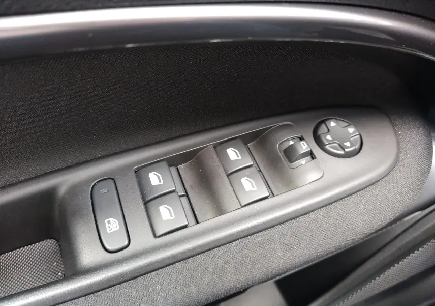 Commande des vitres électriques et réglage des rétroviseurs sur la porte côté conducteur d'une FIAT 600 noire.