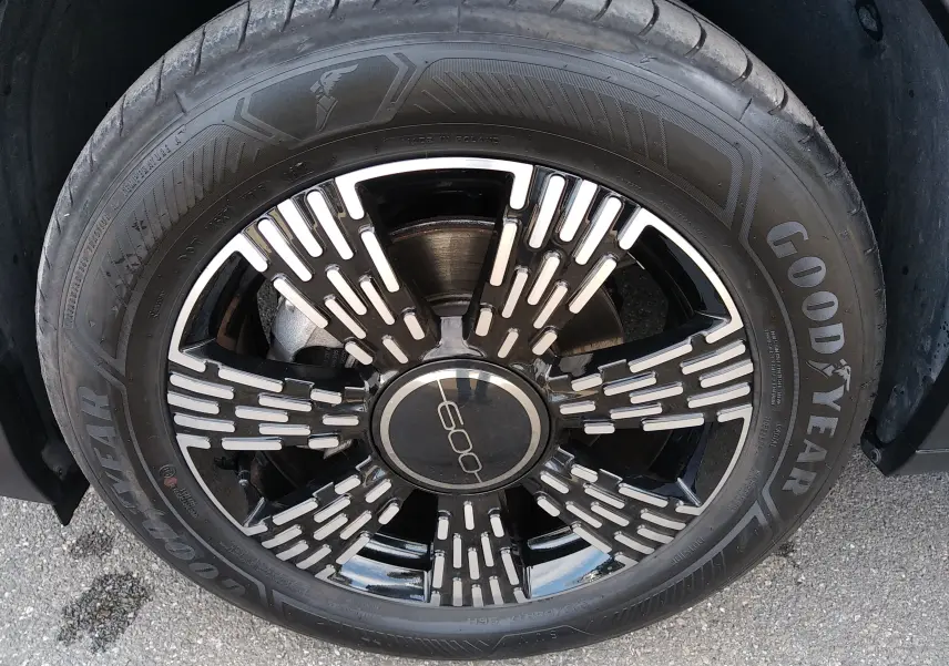 Gros plan sur la jante noire et argentée d'une FIAT 600 noire, mettant en valeur le logo central et le pneu Goodyear.