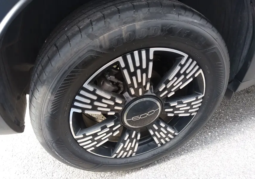 Gros plan sur la roue avant droite noire d'une FIAT 600 2025, avec jante stylisée marquée "600" au centre.
