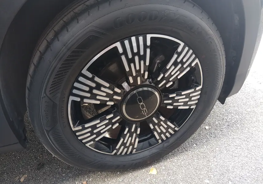 Gros plan sur la roue avant droite noire de la FIAT 600 2025 avec jante au design moderne et logo central distinctif.
