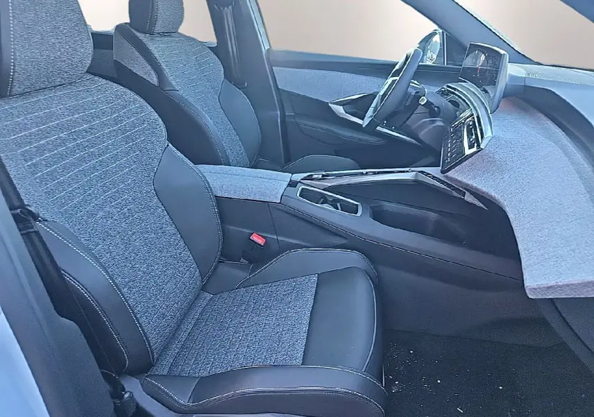 Vue intérieure côté conducteur du Peugeot 5008 Hybrid 145 allure e-dcs6 2025 avec sièges tissu gris et cuir noir.