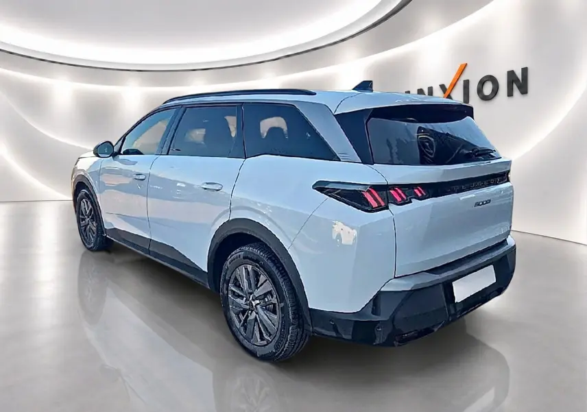 Peugeot 5008 blanc en 3/4 arrière droit, avec feux arrière LED et jantes alliage dans un showroom lumineux.