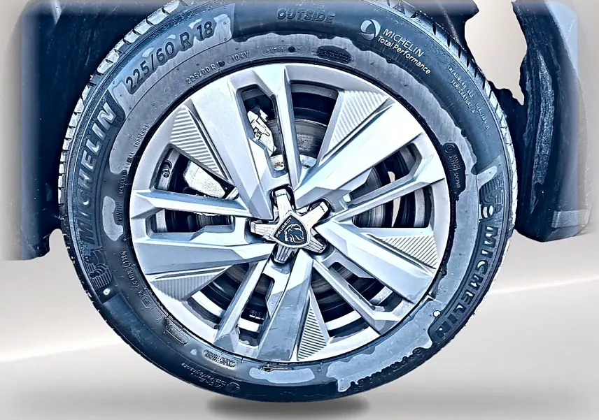 Gros plan sur la jante alu argentée Michelin d’un Peugeot 5008 blanc, mettant en valeur le logo lion au centre.