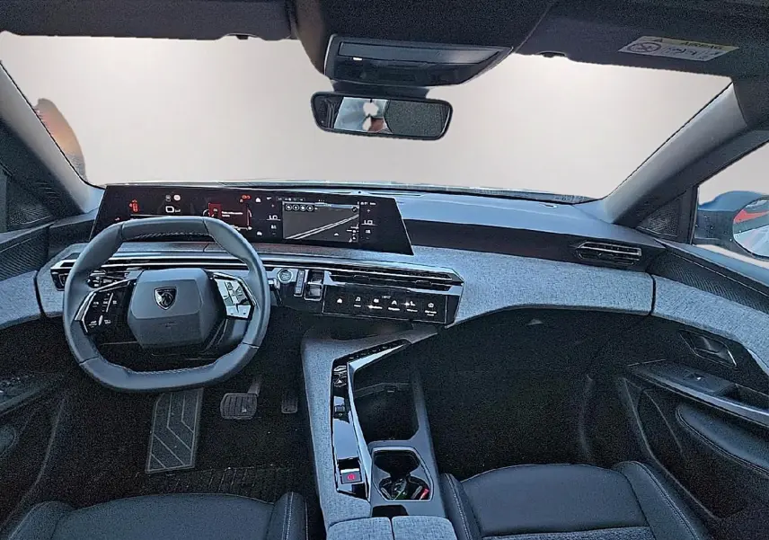 Vue intérieure avant du Peugeot 5008 Hybrid blanc 2025, avec tableau de bord numérique et volant cuir multifonction.