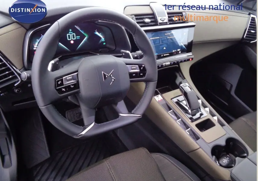 Vue intérieure du poste de conduite du DS7 Crossback avec volant multifonction et console centrale beige et noire.