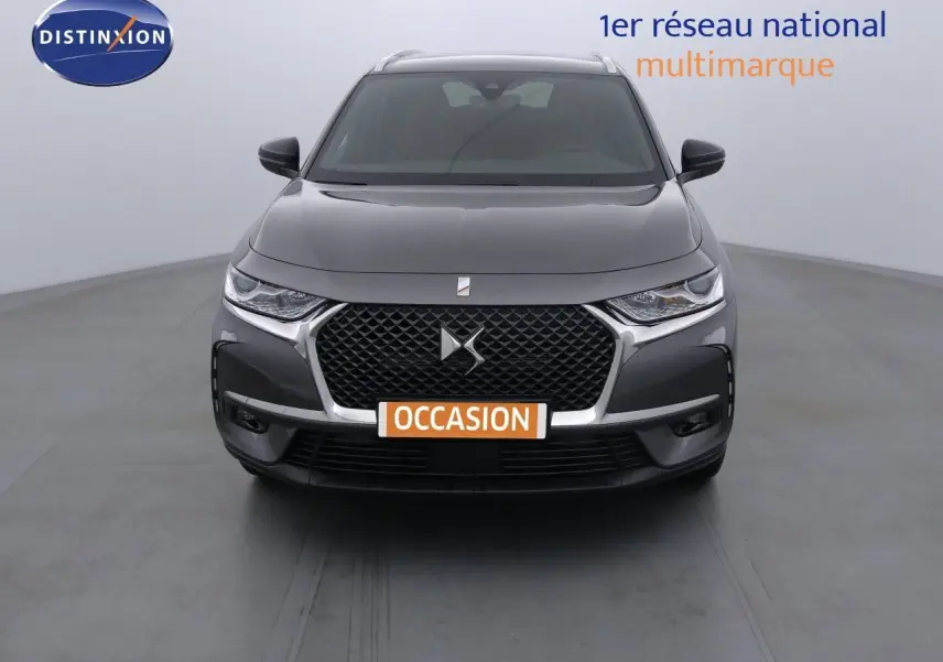 Vue frontale d'un DS7 Crossback gris platinium métal avec calandre distinctive et phares LED allumés.