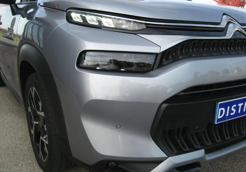 Gros plan sur l'avant droit gris du Citroën C3 Aircross II avec ses phares LED étirés et sa calandre noire texturée.
