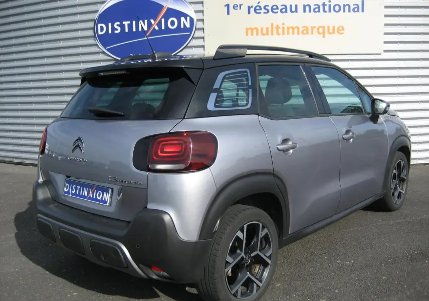 Vue 3/4 arrière droite d'un Citroën C3 Aircross gris 2022 avec toit noir et jantes alliage distinctives.