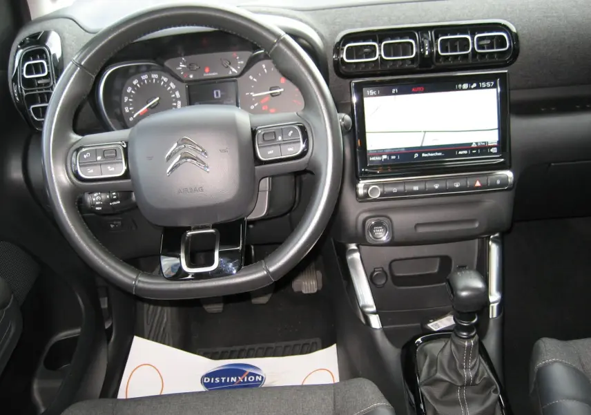 Vue intérieure avant centrée sur le volant noir et la console centrale avec écran tactile du Citroën C3 Aircross gris.