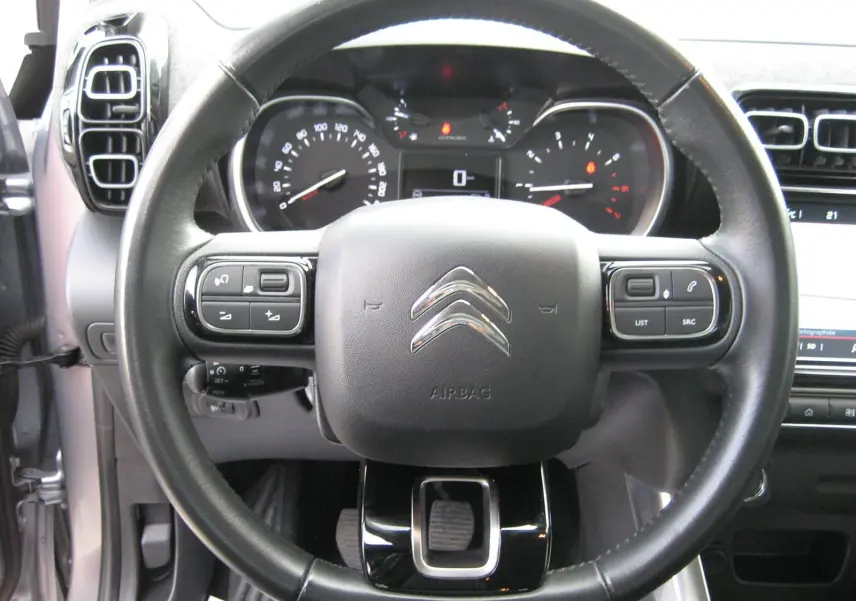 Vue rapprochée du volant noir d'une Citroën C3 Aircross 2022 avec tableau de bord et commandes intégrées visibles.