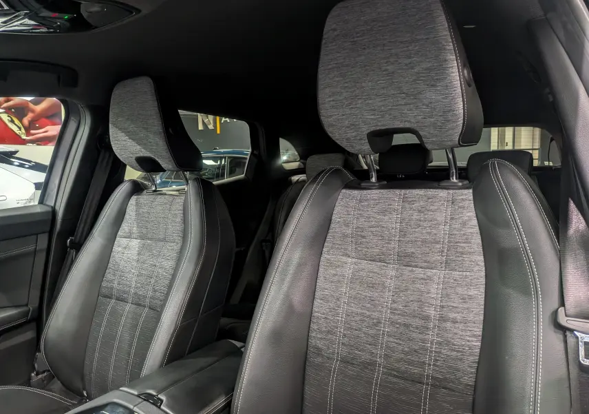 Intérieur du Renault Austral 2024, vue rapprochée des sièges avant en tissu gris et cuir noir avec surpiqûres blanches.