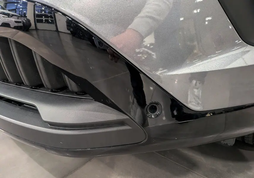 Gros plan sur la partie avant droite gris schiste et noir brillant du Renault Austral 2024 avec capteur de stationnement intégré.