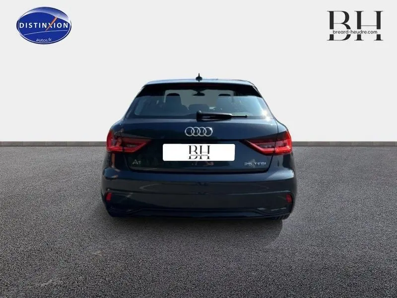 Vue arrière d'une Audi A1 Sportback 25 TFSI Business line noire Mythic métallisée, avec feux LED et logo Audi visible.