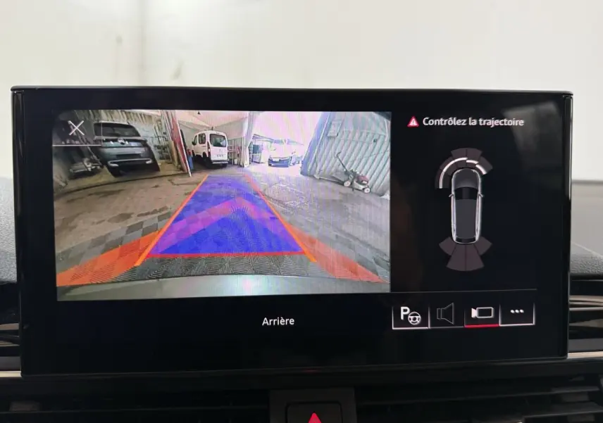 Écran multimédia montrant la caméra de recul avec guidage et alertes sur Audi A4 gris foncé, vue intérieure.