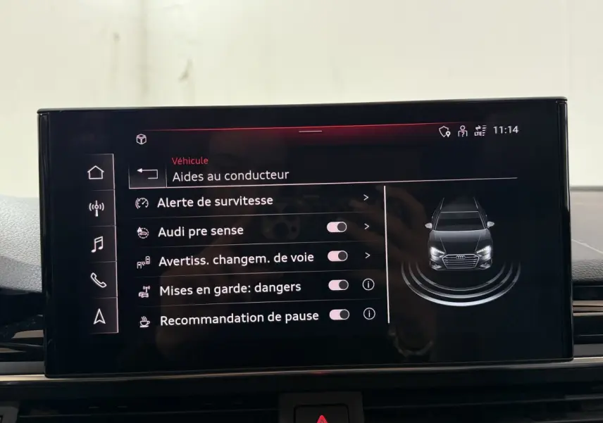 Écran tactile central de l'Audi A4 gris foncé affichant les aides à la conduite avec vue avant stylisée du véhicule.