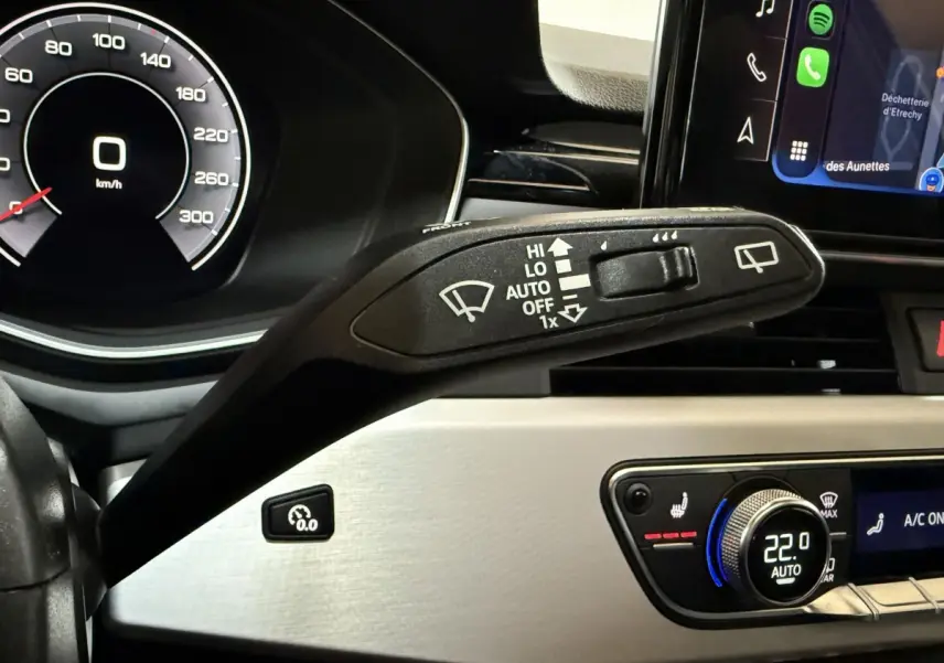Gros plan sur le commodo d’essuie-glace et le tableau de bord numérique d’une Audi A4 gris foncé, intérieur moderne.
