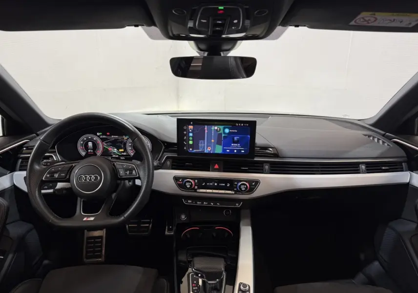 Vue intérieure avant de l'Audi A4 35 TFSI S Edition 2022, tableau de bord noir avec écran tactile central et volant cuir multifonctions.