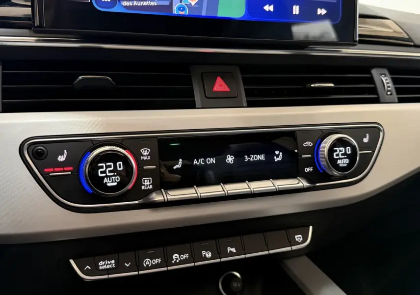 Vue rapprochée du tableau de bord gris clair de l’Audi A4 35 TFSI 2022, affichant la climatisation 3 zones à 22°C.