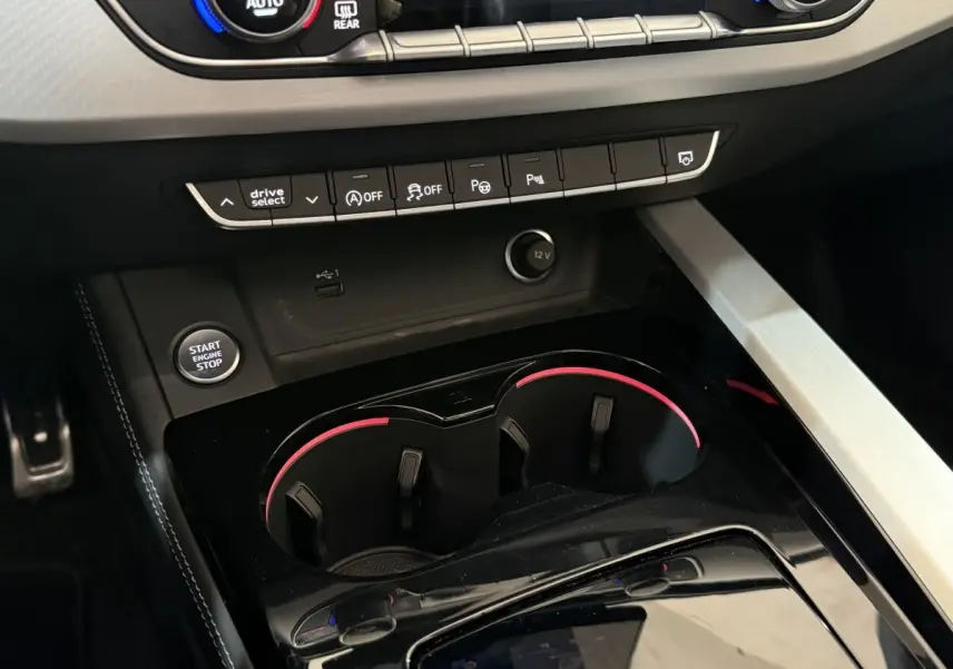 Gros plan intérieur sur la console centrale noire avec boutons de commande et éclairage ambiant rouge, Audi A4 35 TFSI 2022.