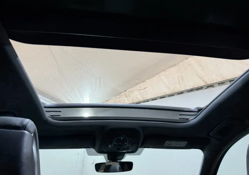 Vue intérieure vers le toit ouvrant panoramique de l'Audi A4 gris foncé, avec ciel lumineux visible à l'extérieur.