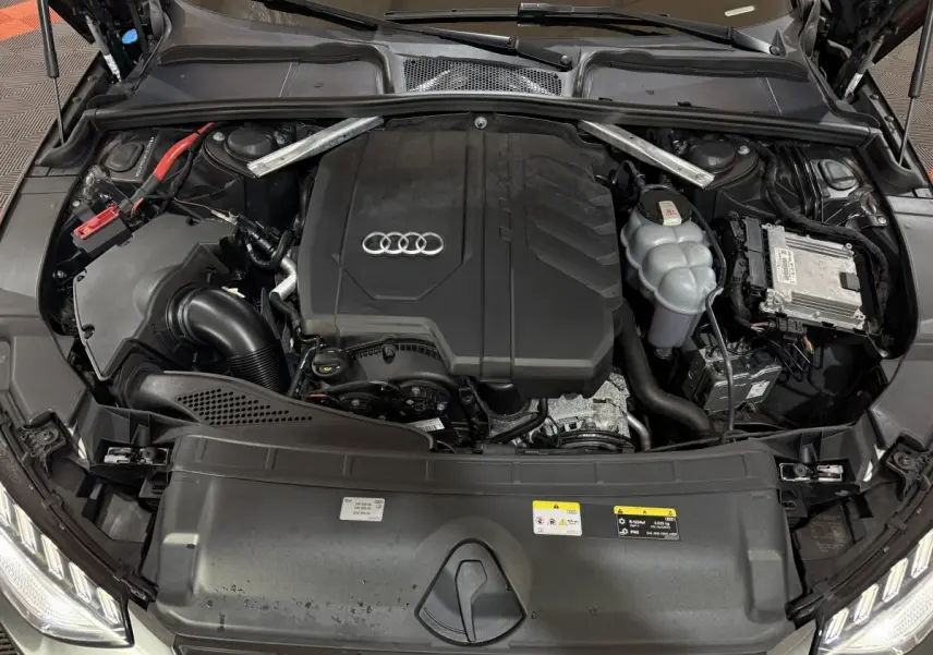 Vue plongeante sur le moteur gris foncé d’une Audi A4 35 TFSI 150 S tronic S Edition avec logo Audi visible.