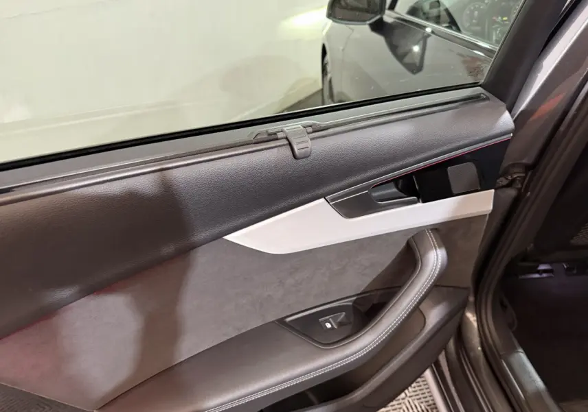 Vue intérieure du panneau de porte arrière droite gris foncé de l'Audi A4 35 TFSI avec insert argenté et commande de vitre.