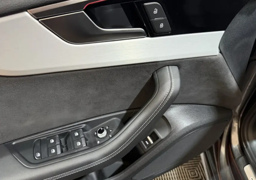Gros plan sur la porte avant gauche gris foncé d’Audi A4 avec commandes des vitres et verrouillage.