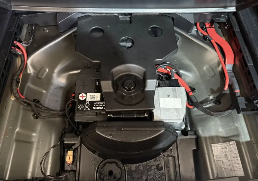 Vue plongeante sur le compartiment batterie gris métallique avec câbles rouges d’une Audi A4 35 TFSI hybride 2022.