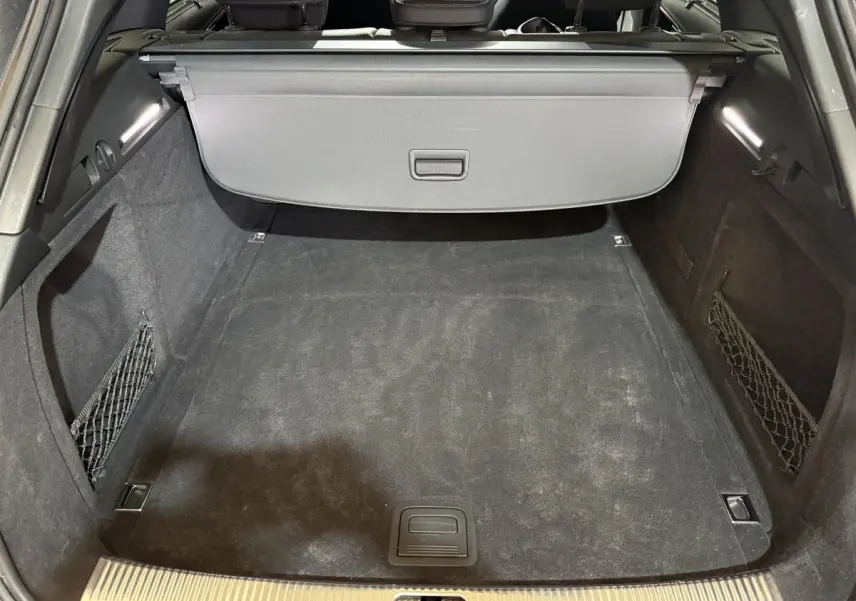 Coffre spacieux gris foncé d’Audi A4 35 TFSI S Edition avec filets latéraux et cache-bagages rétractable.
