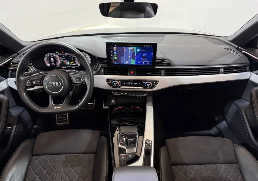 Vue intérieure avant de l'Audi A4 gris foncé 35 TFSI avec tableau de bord digital et écran tactile central.