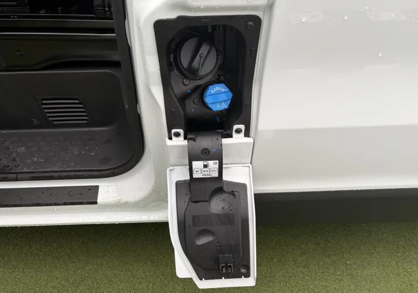 Gros plan sur la trappe à carburant ouverte côté gauche du Renault Trafic blanc glacier, avec bouchon AdBlue visible.
