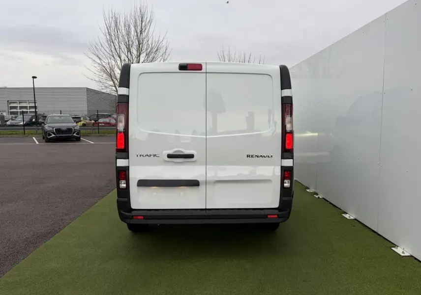 Vue arrière du Renault Trafic Fourgon blanc glacier avec portes arrière tôlées et feux verticaux allumés.