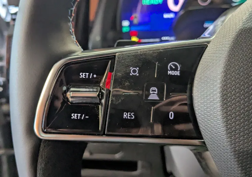 Gros plan sur les commandes du volant à gauche du Renault Austral E-Tech 200 gris schiste, avec boutons de régulateur et mode.