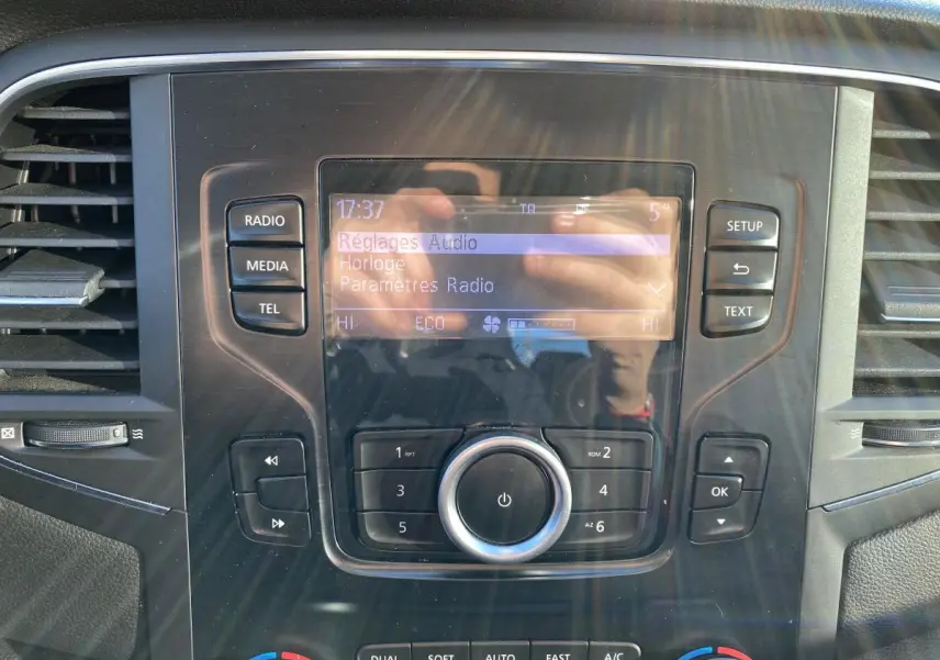Vue rapprochée du tableau de bord de la Renault Mégane 2017, écran central avec réglages audio et commandes autour.
