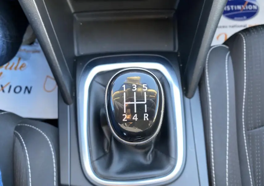 Le levier de vitesses manuel noir de la Renault Mégane gris platine, vu en gros plan depuis le dessus.