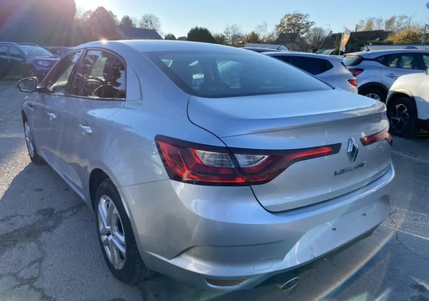 Vue 3/4 arrière droite d'une Renault Mégane Sedan gris platine 2017 avec feux arrière LED et hayon lisse.