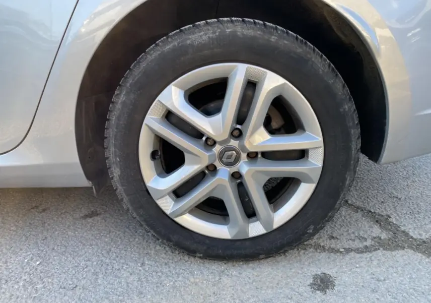 Gros plan sur la roue avant gauche de la Renault Mégane gris platine, avec jante alliage à cinq branches doubles.