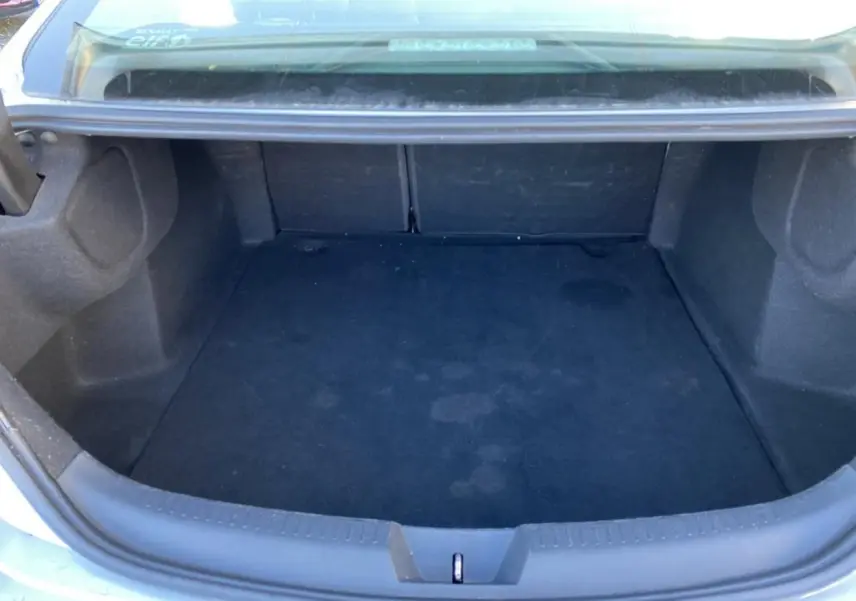 Coffre ouvert vu de l'arrière d'une Renault Mégane Sedan gris platine, montrant un espace de rangement vide.