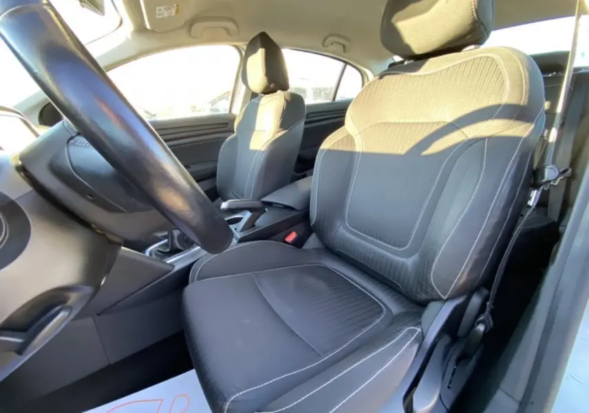 Vue intérieure côté conducteur de la Renault Mégane Sedan 2017, sièges noirs avec surpiqûres blanches et volant visible.