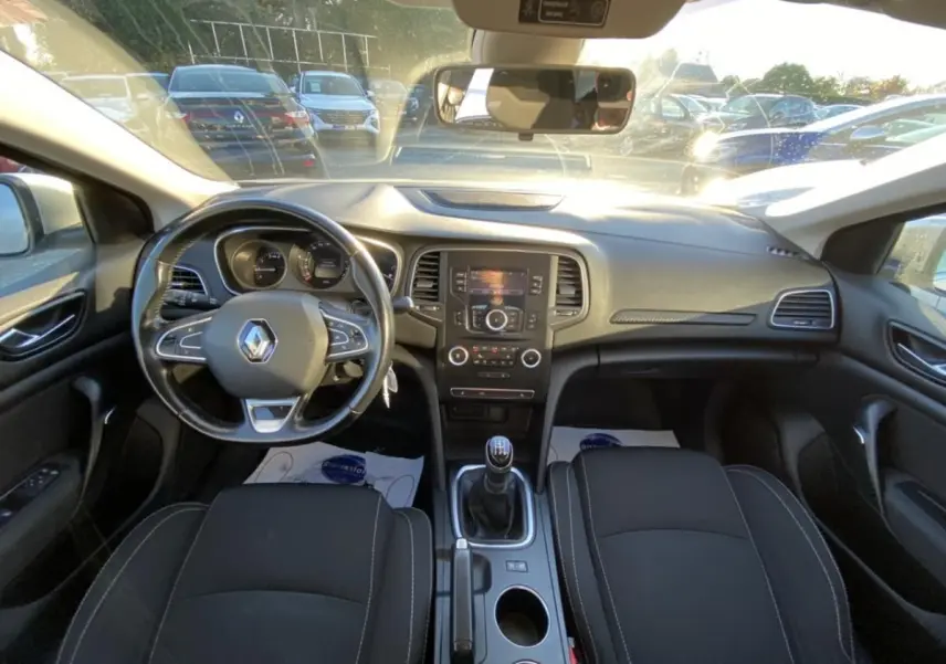 Vue intérieure avant de la Renault Mégane gris platine, tableau de bord avec volant multifonction et boîte manuelle.