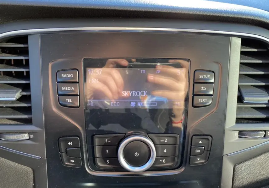 Tableau de bord de Renault Mégane gris platine, zoom sur l'écran central avec commandes radio et climatisation.