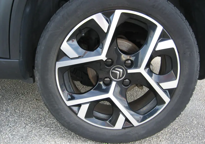 Gros plan sur la jante noire et argentée avec logo Citroën du SUV gris platinium C3 Aircross 2022.
