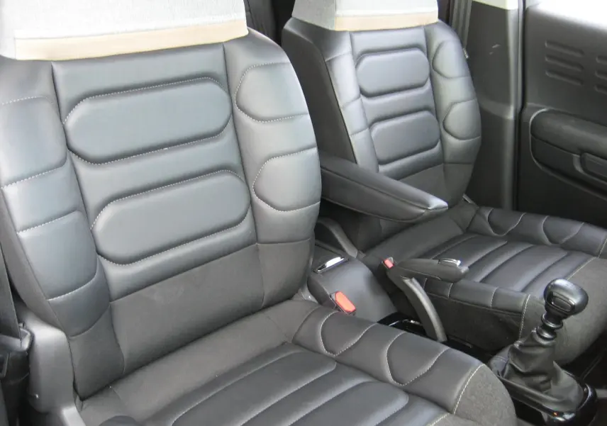 Vue rapprochée des sièges avant en cuir noir du Citroën C3 Aircross gris platinium, avec levier de vitesse manuel visible.
