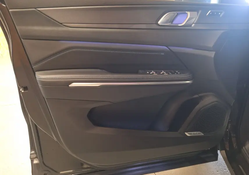 Vue rapprochée de la porte avant gauche noire du LYNK & CO 01 2023 avec commandes de vitres et haut-parleur intégré.