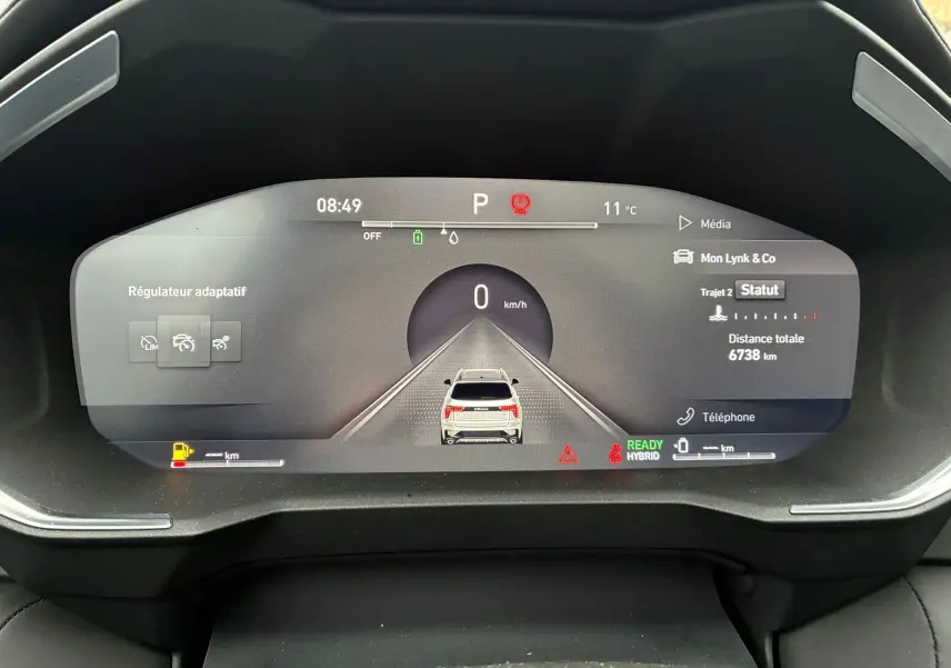 Affichage numérique du tableau de bord du Lynk & Co 01 hybride rechargeable, montrant la vitesse à 0 km/h et l'état du régulateur adaptatif.